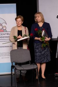 dwie kobiety stojące na scenie z kwiatami
